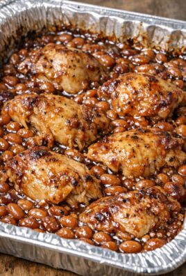 Cuisses de poulet BBQ servies avec haricots au four dans un plat en aluminium